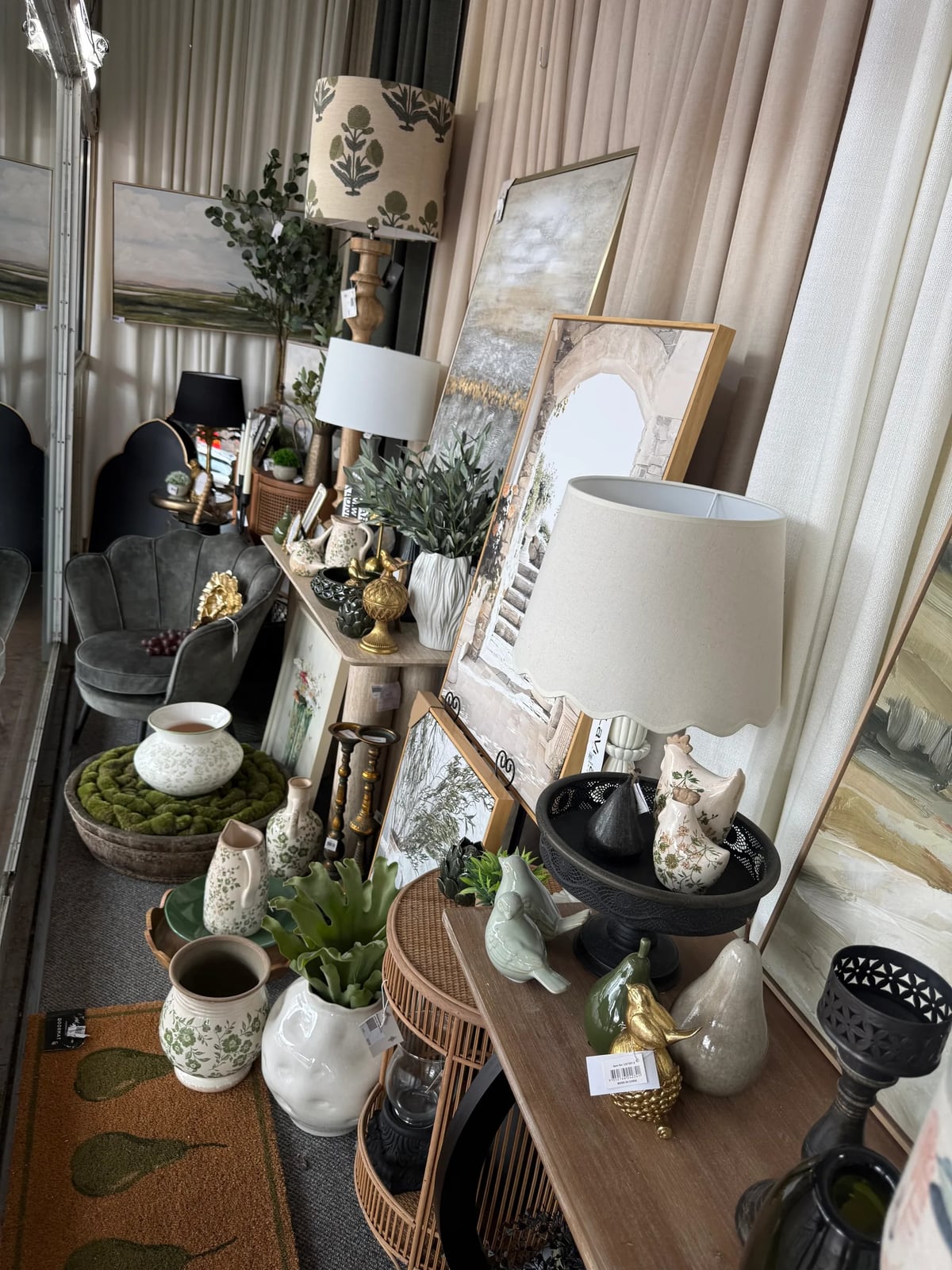 Showroom display of lamps, ceramics, framed prints and a grey armchair