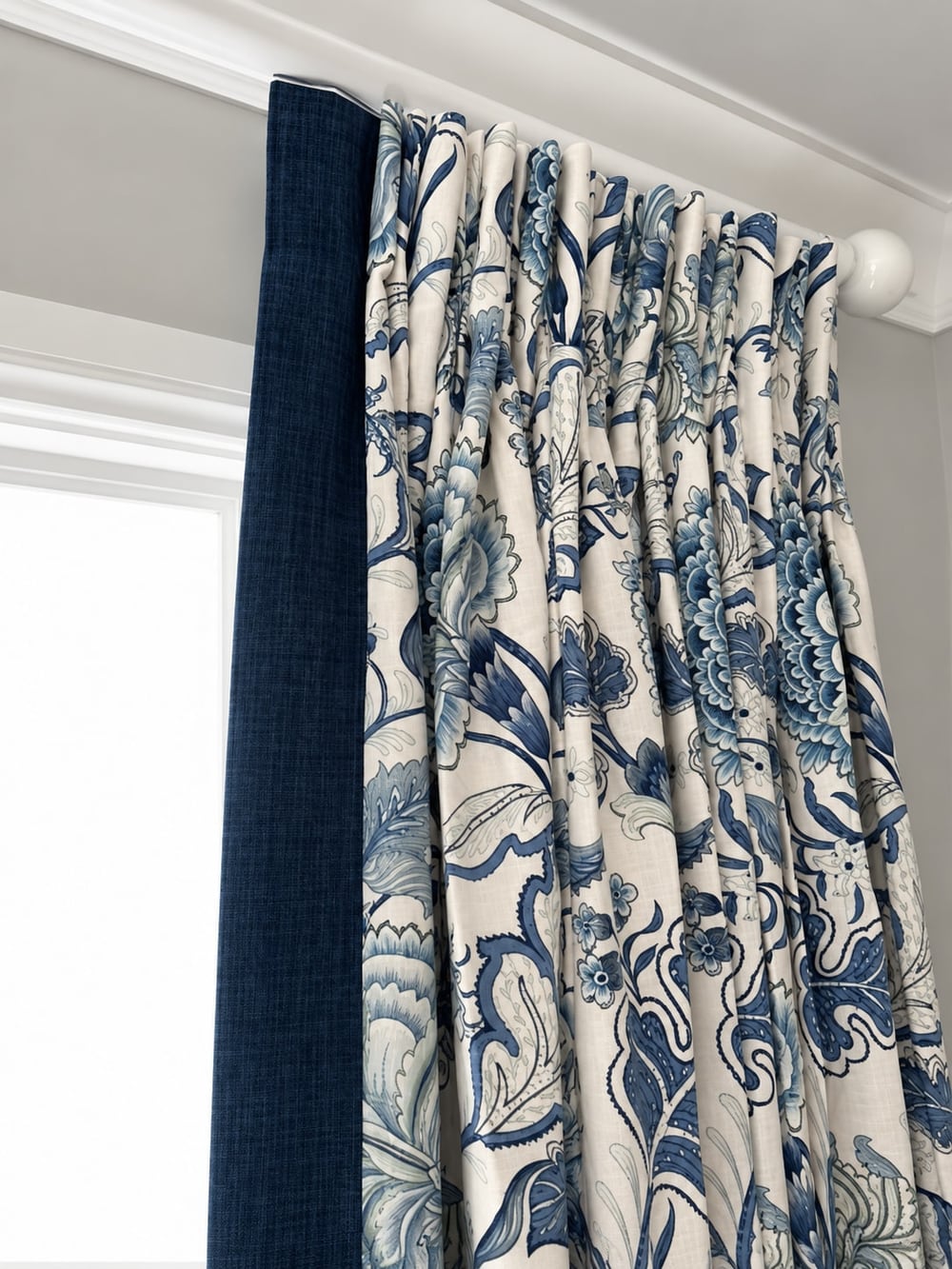 Pencil-pleat curtain heading in blue floral fabric with a navy leading edge
