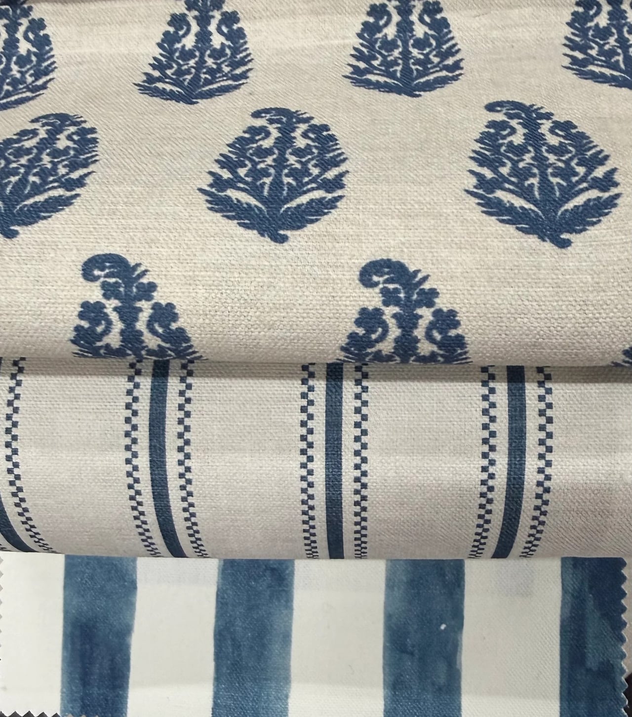 Folded cream and navy printed fabric samples stacked in layers