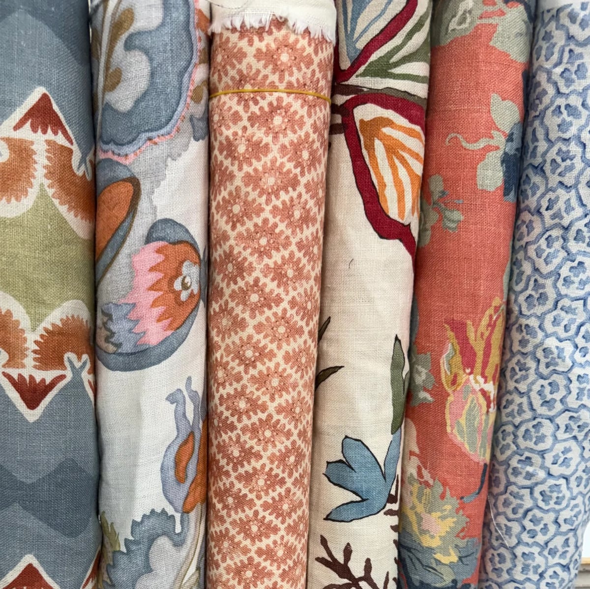 Stacked fabric bolts with floral, geometric and coral patterns in the showroom