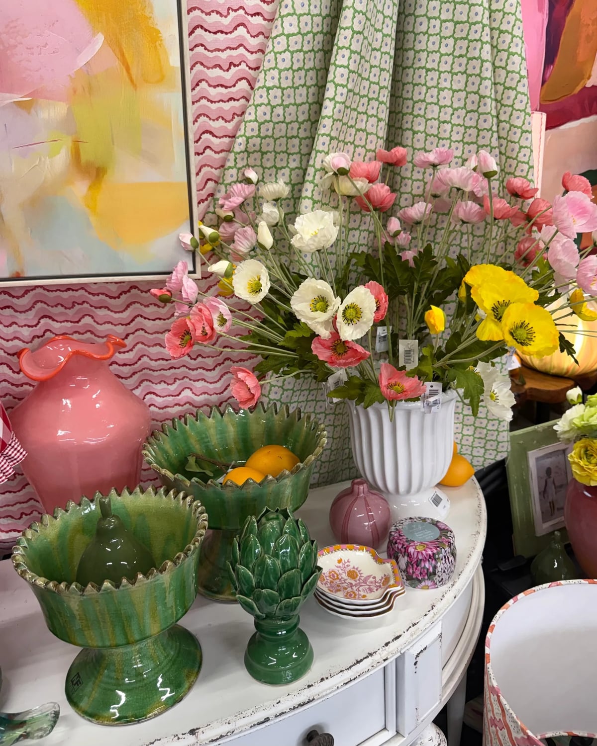 Showroom giftware table with green ceramic bowls, a pink vase and mixed flowers