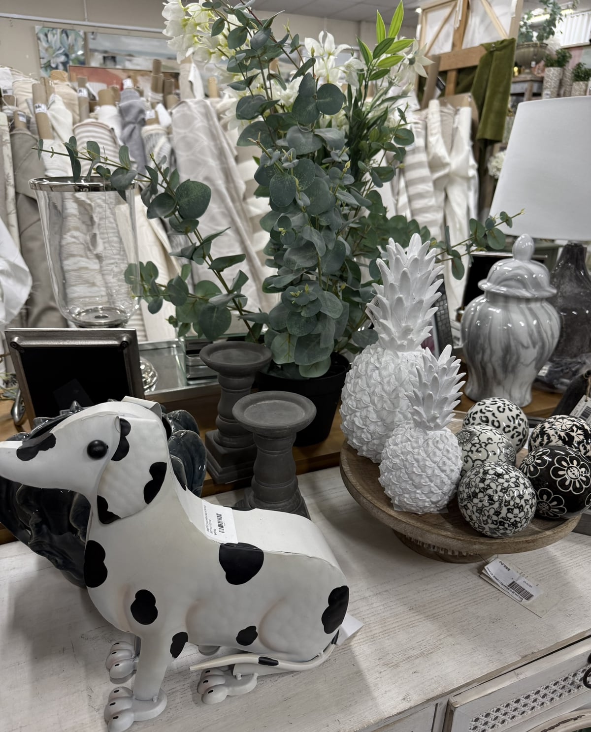 Dalmatian figurine, white pineapple ornaments and fabric rolls on a showroom table
