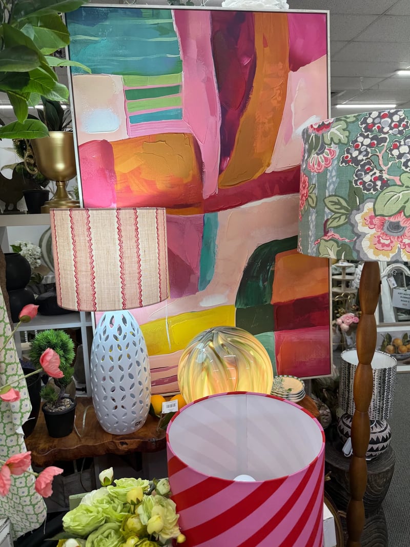 Assorted lampshades and lamps in front of a colourful abstract painting