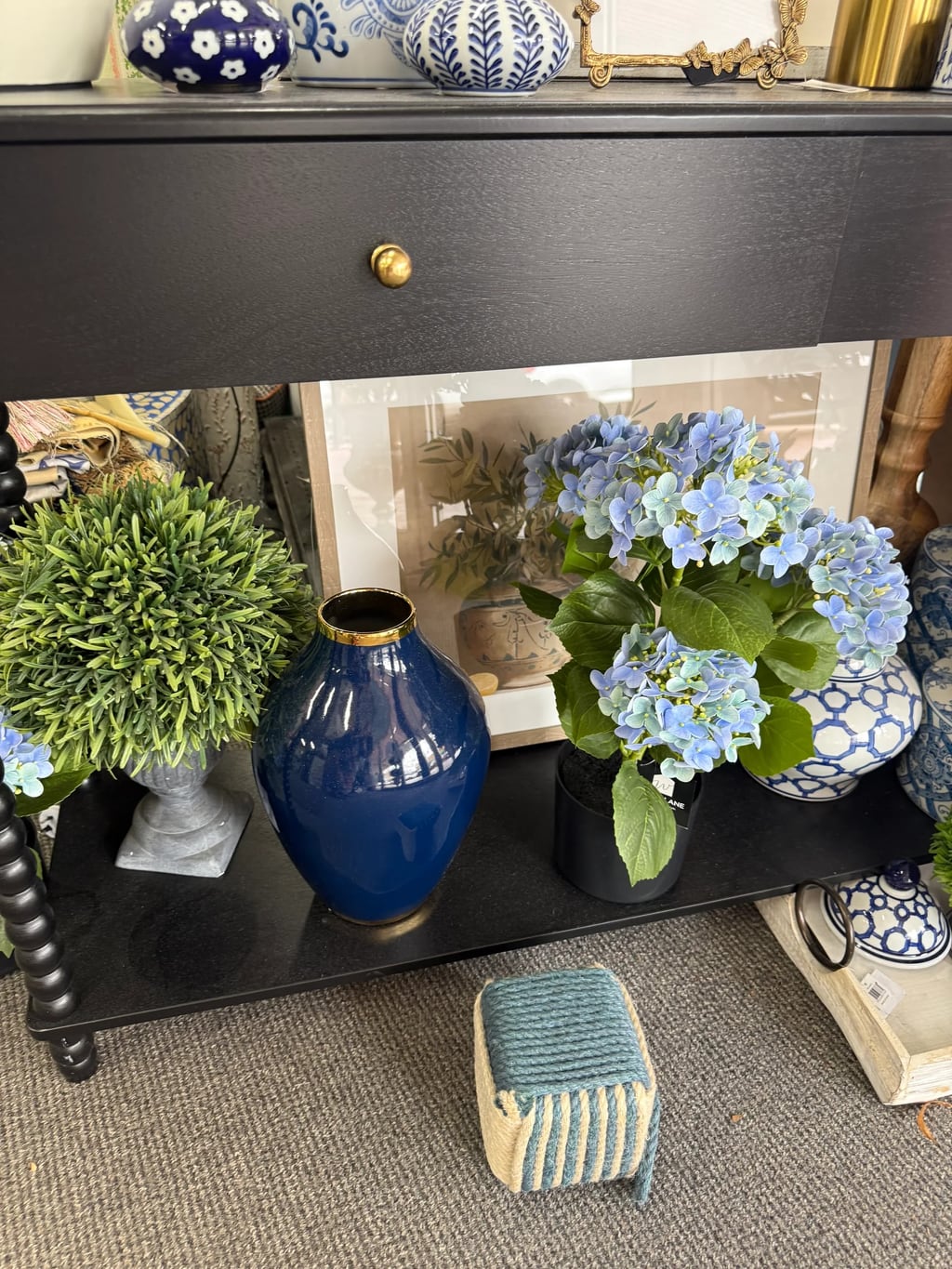 Navy vase, hydrangeas and blue-and-white ceramics on a black showroom console